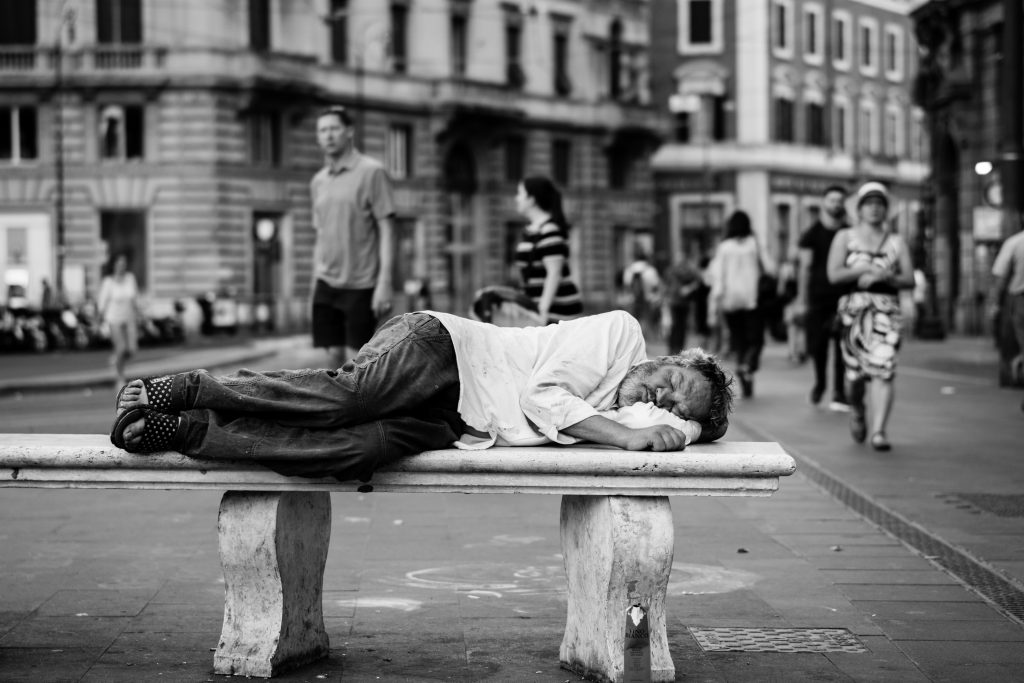 Homeless man sleeping on public bench